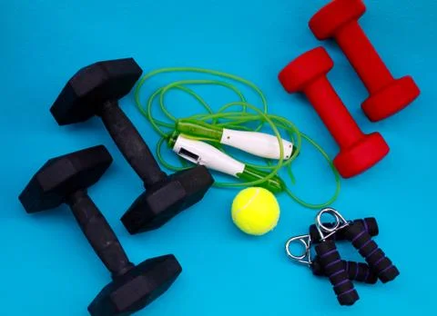 Exercise equipment weights, jump rope, tennis ball, hand grip strengthener. Stock Photos