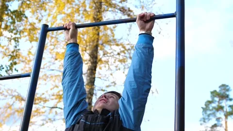 Exercise in the fresh air. Young strong guy doing exercises on the bar. Autumn Vidéo 95643254