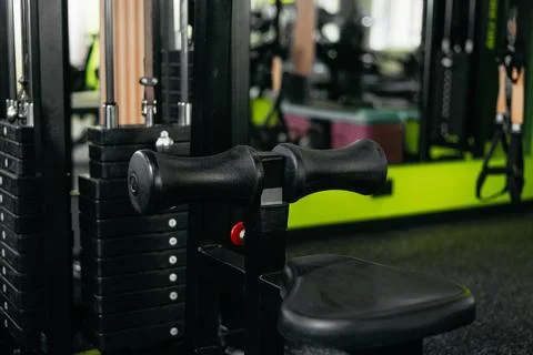 An exercise machine is set up in a gym with various weights stacked nearby. The Stock Photos