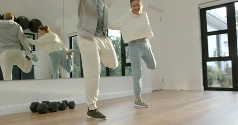 Exercise partners balancing by mirrored wall in workout clothes while Stock Footage 345589624