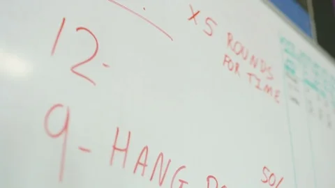 Exercise personal trainer writing gym exercises on white board Vidéo 80534465