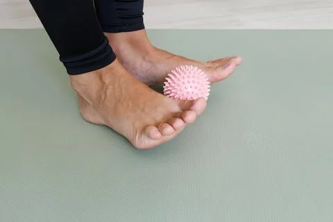 Exercise with a spiky massage ball held between the forefeet to train toe gri Stock Photos