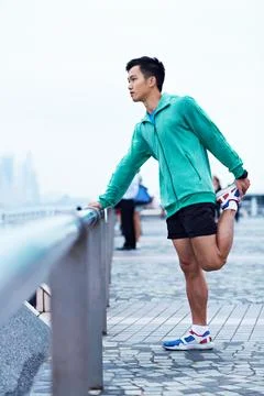 Exercise, thinking and Asian man in city stretching for fitness, workout and Stock Photos