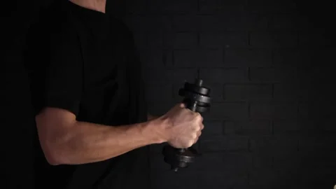 Exercise with weights on a black background. A play of light and shadow. A man o Stock Footage 147176539