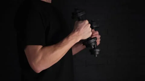 Exercise with weights on a black background. A play of light and shadow. A man o Stock Footage 147176634