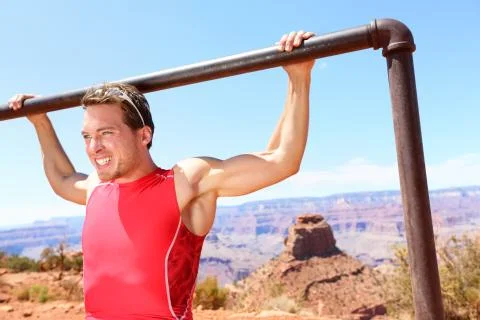 Exercising athlete doing pull ups in nature Stock Photos