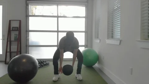 Exercising man throwing down medicine ball as camera pulls back Video stock 90828204