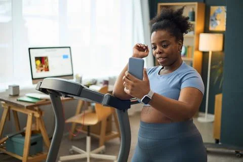 Exercising on Treadmill While Using Smartphone and Smartwatch 写真素材