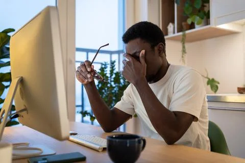 Exhausted afro software engineer take off glasses rub eyes, nose tired after 写真素材