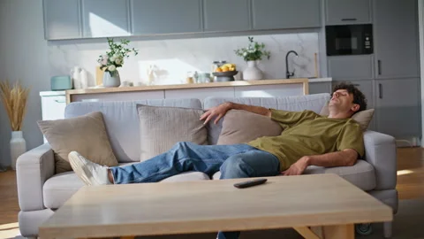 Exhausted brunette falling sofa feeling relaxed at home. Tired man lying couch Stock Footage 289144750