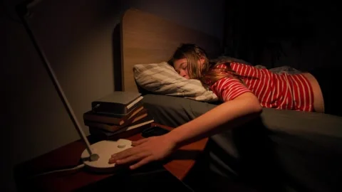 Exhausted child turning off bedside lamp falling asleep in the dark Stock Footage 336671723