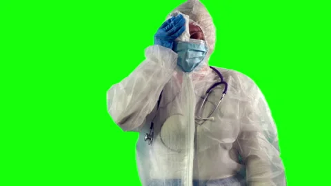 Exhausted doctor is taking off a face shield and wipes sweat with a napkin after Stock-Footage 148292403