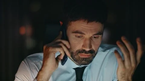 Exhausted employee talking smartphone solving business problem at night close up Stock Photos