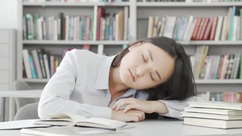 Exhausted female student dozing off while studying in the library Stock Footage 311922895