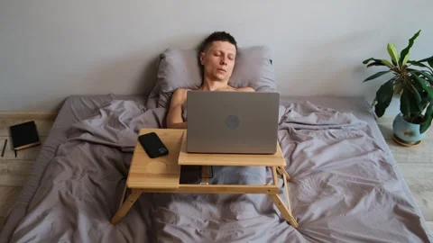 Exhausted freelancer falls asleep while working hard in bed remote work from Stock Footage 314515724