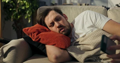 Exhausted guy after hard day's work lying on the couch. The sun is shining in 库存影片 218280525