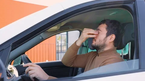 Exhausted guy sits behind the wheel and rubs his eyes with one hand, the other Stock Footage 300255567