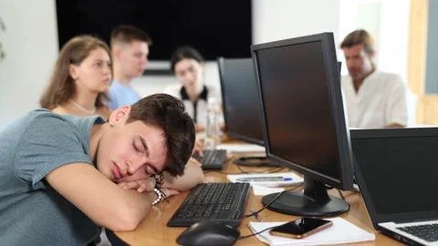 Exhausted guy student sits at table, puts head on crossed arms and sleeps after Stock Footage 274114077