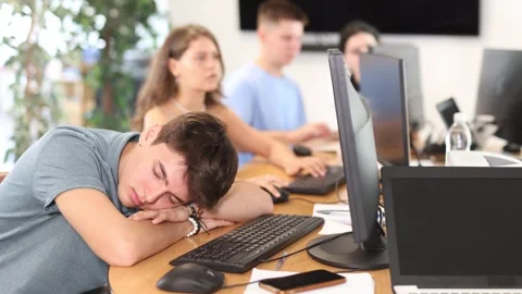 Exhausted guy student sits at table, puts head on crossed arms and sleeps after Stock Footage 308963968