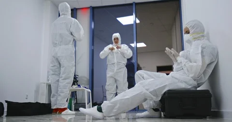 Exhausted hospital staff in hazmat PPE suits resting. Covid-19 coronavirus Stock Footage