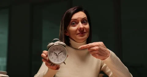 Exhausted lady points at alarm clock staying late at work Stock Footage 274795499
