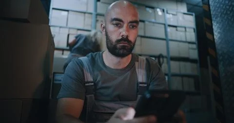 Exhausted Loader Using Smartphone, Having Rest after Hard Workday in Logistics Foto stock