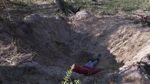An exhausted man falls into a muddy pit while jogging and lies there lifeless. Stock-Footage 315160431