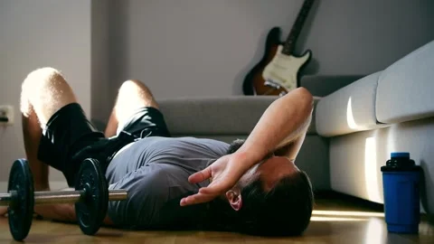 Exhausted man lying on floor after heavy work out in home gym. Footage FHD Stock Footage 147052300