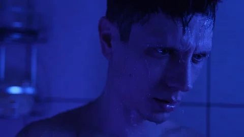Exhausted man standing under shower, deep in thought after an emotionally Stock Footage 304236058