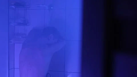 Exhausted man standing under shower, deep in thought after an emotionally Stock Footage 305312667