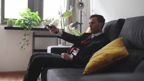 Exhausted man in suit watching in the sofa static shot Stock Footage 153932759