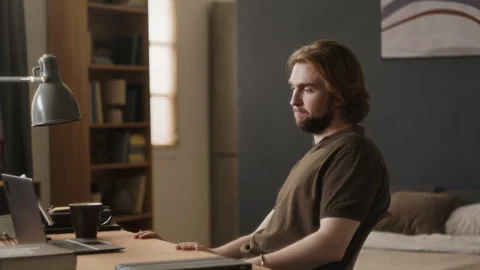 Exhausted Man Working on Laptop with Coffee Cup at Home Office Stock Footage 345515741