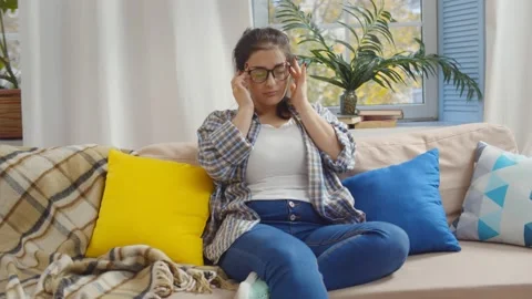 Exhausted mother sitting on couch while kids running at home Stock Footage 142393036