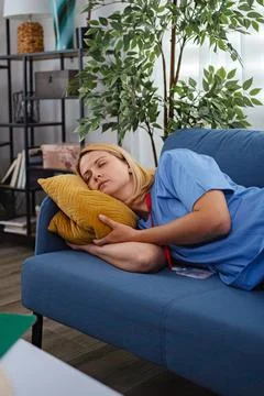 Exhausted Nurse Sleeping on Sofa After Long Shift at Hospital Stock Photos