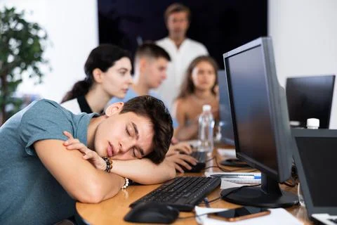Exhausted young employee engaged in software development sleeping at workplace Stock Photos