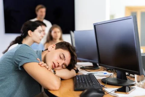 Exhausted young employee engaged in software development sleeping at workplace Stock Photos