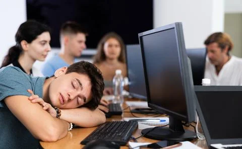 Exhausted young employee engaged in software development sleeping at workplace Stock Photos