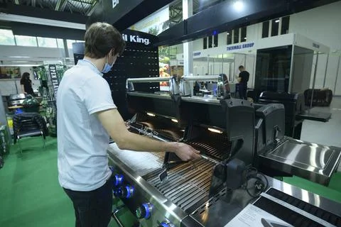 Exhibitor checking modern grill presented on stand. Exhibition Stock Photos