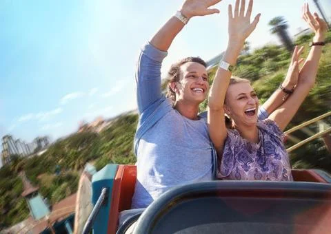 Exhilarated young couple riding amusement park ride Stock Photos