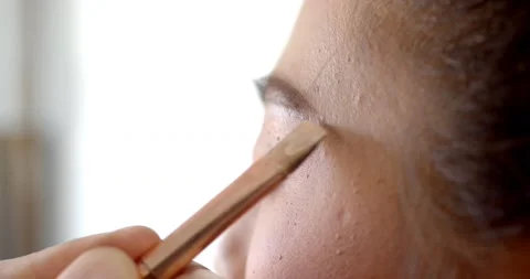 ExHold a medium-sized, flat-tip brush to remove excess from the brow line. Stock Footage 222740758