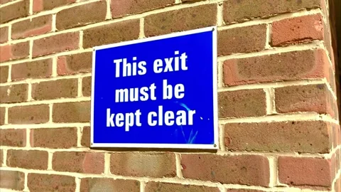 This exit must be kept clear blue square sign with white text font on brick wall Stock Footage 342255373