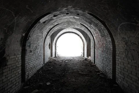 Exit from the old dark brick arched tunnel of the 19th century fortification. Stock Photos