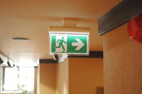 Exit sign indicating direction in a building hallway Stock Photos