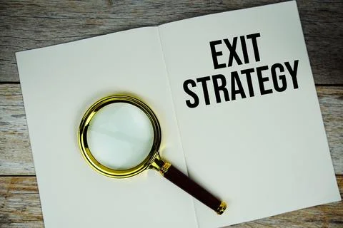 Exit Strategy text message written on paper note with magnifying glass top .. Stock Photos