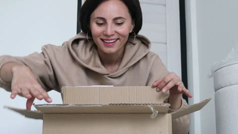 Exited woman checking a parcel, looking inside the open a cardboard box at home Stock Footage 255590004