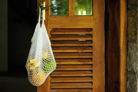 Exotic Fruit Bunch in String Bag on Wooden Door Stock Photos