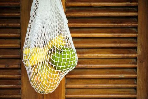 Exotic Fruit Bunch in String Bag on Wooden Door Stock Photos
