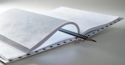 Expanded checkered notebook with open sheets and pencil. Selective focus. Blu Foto stock