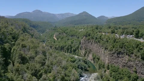 Expanding shot over a winding mountain river cutting through a deep forested Stock Footage 336269134