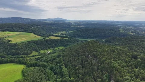 Expansive aerial view over rolling hills and patchwork farmland with distant Stock Footage 346261510